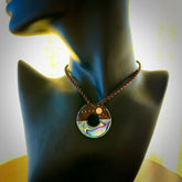 This photo shows a donut disc pendant hand carved from Lignum Vitae with premium nz paua shell, Mother of Pearl alongside; brass, copper and silver. This is a stand out one off necklace for those who appreciate art to wear. It is provided with a cord in brown that is a fixed length with Paua Shell Toggle. We ship this piece worldwide and shipping is included in the price.